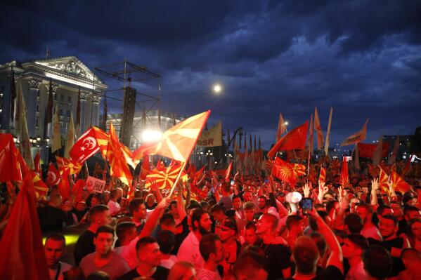 Supporters of the opposition VMRO-DPMNE party wave party and national flags in front of the government building in Skopje, North Macedonia, on Saturday, June 18, 2022. Thousands of opposition supporters have gathered late on Saturday for anti-government protest in downtown of North Macedonia's capital Skopje in a bid to press leftist government on snap elections, two years earlier of regular term. (AP Photo/Boris Grdanoski)