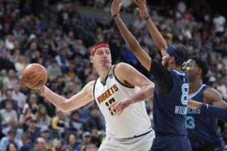 FILE - Denver Nuggets center Nikola Jokic looks to pass the ball as Memphis Grizzlies guard Ziaire Williams, front, and forward Jaren Jackson Jr. defend during the first half of an NBA basketball game April 7, 2022, in Denver. Jokic and the Nuggets agreed Thursday, June 30, to a $264 supermax extension, according to a person with direct knowledge of the negotiations who spoke to The Associated Press on condition of anonymity because neither the player nor team announced the agreement. (AP Photo/David Zalubowski, File)