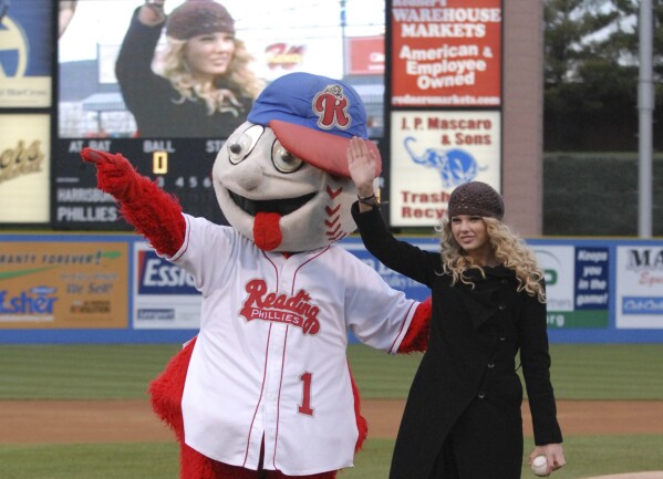 This photo provided by the Reading Fightin Phils shows Taylor Swift gesturing beside the team mascot, Screwball, before a Reading Fightin Phils minor league baseball game at First Energy Stadium in Reading, Pa., April 5, 2007. (Reading Fightin Phils via AP)