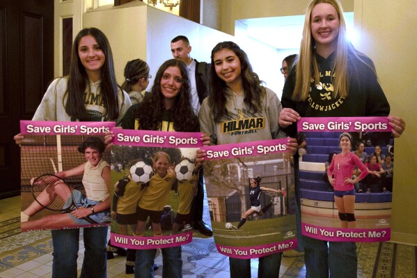 Student athletes hold signs during a hearing to consider bills to pass rules banning transgender student-athletes Tuesday, April 1, 2025, in Sacramento, Calif. (AP Photo/Yuri Avila)