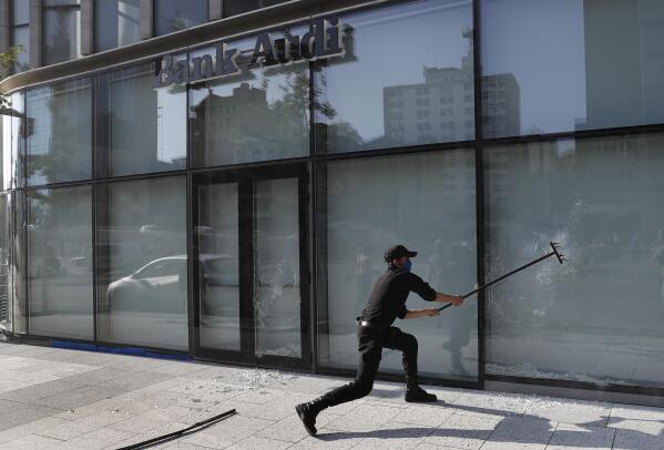 FILE - An anti-government protester destroys a bank window during a protest against the deepening financial crisis, in Beirut, on April 28, 2020. Angry protesters in Lebanon Thursday Feb. 16, 2023 smashed windows and set tires on fire outside two of the country's biggest banks in the capital city, as the value of the local currency hit a new low and poverty deepens. (AP Photo/Hussein Malla, File)