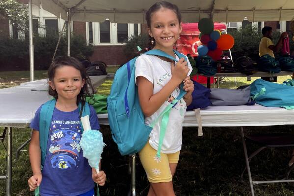 From left, sisters Audrey and Jubilee Colon pick out new backpacks at a Chicago Public Schools back-to-school supply giveaway at Theodore Roosevelt High School in Chicago, on July 22, 2022. This back-to-school shopping season, parents, particularly in the low-to-middle income bracket, are focusing on the basics like no-frills rain boots, while also trading down to cheaper stores, including second-hand clothing, as surging inflation takes a toll on their household budgets. (AP Photo/Claire Savage)