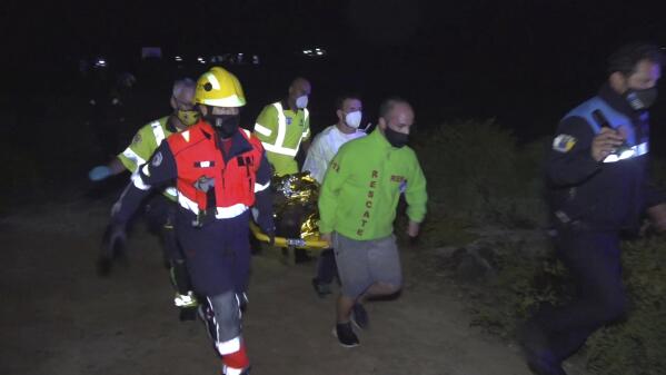 Emergency service members carry the body of a migrant after been rescued at the island of Lanzarote in the Spain's Canary Islands on Friday, Jun 18, 2021. Spanish authorities say four people have died including a child after a migrant boat believed to be carrying 45 passengers capsized near Spain's Canary Islands. The boat was approaching Órzola on the island of Lanzarote on Thursday night when it flipped over a few meters (yards) from shore, throwing the passengers into the water. (Europa Press via AP)