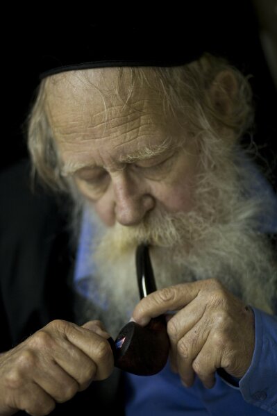 In this file photo taken on Nov. 10, 2010, Rabbi Adin Steinsaltz smokes a pipe during an interview with The Associated Press in Jerusalem. Steinsaltz, a prolific Jewish scholar who spent 45 years compiling a monumental and ground-breaking translation of the Talmud, has died. He was 83. Steinsaltz wrote more than 60 books on subjects ranging from zoology to theology. (AP Photo/ Bernat Armangue, File)