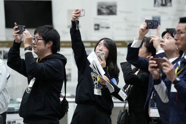 Staff of Japan Aerospace Exploration Agency (JAXA) watch a live streaming of the pinpoint moon landing operation by the Smart Lander for Investigating Moon (SLIM) spacecraft observe a live streaming at JAXA's Sagamihara Campus Saturday, Jan. 20, 2024, in Sagamihara near Tokyo. Japan's space agency said early Saturday that its spacecraft is on the moon, but is still "checking its status." More details will be given at a news conference, officials said. (AP Photo/Eugene Hoshiko)