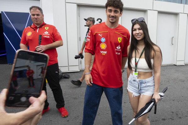 Ferrari driver Charles Leclerc poses for a photo with a fan at the F1 Canadian Grand Prix auto race, Thursday, June 6, 2024 in Montreal. (Ryan Remiorz/The Canadian Press via AP)
