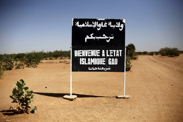 FILE - A sign on the northern road exiting in Gao, Northern Mali, reads "welcome to the islamic state of Gao on Jan. 30, 2013. Islamic State extremists have almost doubled the territory they control in Mali in less a year, and their al-Qaida-linked rivals are also capitalizing on the deadlock and perceived weakness of armed groups that signed a 2015 peace agreement, United Nations experts said in a new report.(AP Photo/Jerome Delay, File)