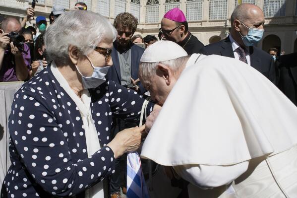 Pope Francis leans and kiss a tattoo on the arm of Holocaust survivor Lidia Maksymowicz, a Polish citizen who was deported to Auschwitz from her native Belarus, during his weekly general audience at the Vatican, Wednesday, May 26, 2021. Pope Francis has kissed the tattoo of an Auschwitz survivor during a general audience on Wednesday. Lidia Maksymowicz, a Polish citizen who was deported to Auschwitz from her native Belarus, showed the pope the number tattooed on her arm by the Nazis, and Francis leaned over and kissed it Wednesday. Maksymowicz told Vatican News that she did not exchange words with the pope.  She said “we understood each other with a glance."   (Vatican Media via AP)