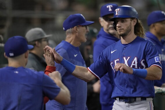 Texas Rangers' Travis Jankowski, right, is congratulated after scoring against the Oakland Athletics during the seventh inning of a baseball game in Oakland, Calif., Monday, Aug. 7, 2023. (AP Photo/Jeff Chiu)