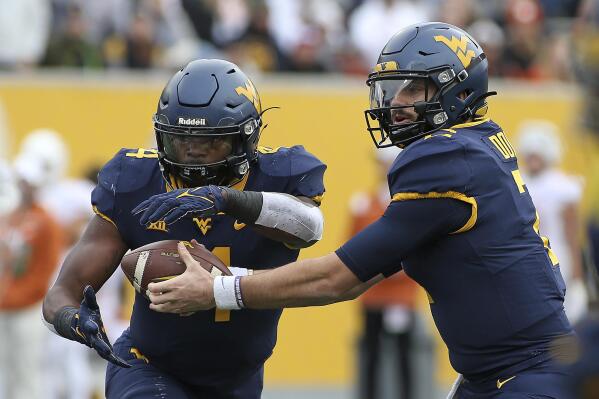 West Virginia quarterback Jarret Doege (2) hands the ball off to running back Leddie Brown (4) during the first half of an NCAA college football game against Texas in Morgantown, W.Va., Saturday, Nov. 20, 2021. (AP Photo/Kathleen Batten)