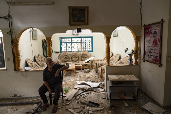 Bir Filistinli, 27 Ekim 2023 Cuma günü Gazze Şeridi'nin güneyindeki Han Yunus'ta İsrail'in hava saldırısı sonrasında hasar gören evinde oturuyor.  (AP Fotoğrafı/Fatima Şpir)