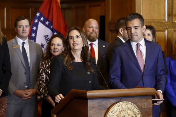 Arkansas Gov. Sarah Huckabee Sanders, center, along with Patrick Howarth of ExxonMobil, addresses ExxonMobil's announcement that it will begin drilling for lithium in southern Arkansas, with the oil giant expected to begin production of the critical material for electric vehicles by 2027, at a news conference at the state Capitol, Monday, Nov. 13, 2023, in Little Rock, Ark. (Thomas Metthe/Arkansas Democrat-Gazette via AP)