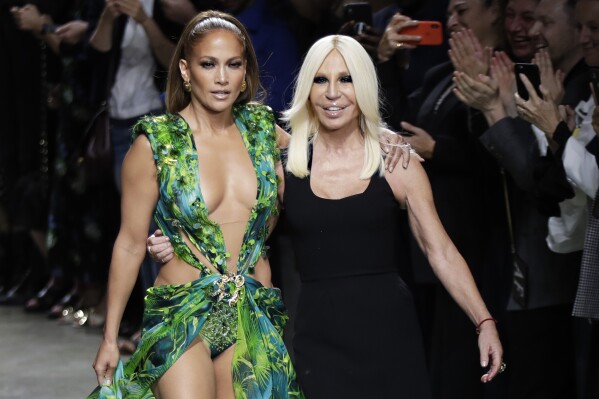 Actress Jennifer Lopez, left, and designer Donatella Versace accept applause at the conclusion of the Versace Spring-Summer 2020 collection, unveiled during the fashion week, in Milan, Italy, Friday, Sept. 20, 2019. (AP Photo/Luca Bruno, File)