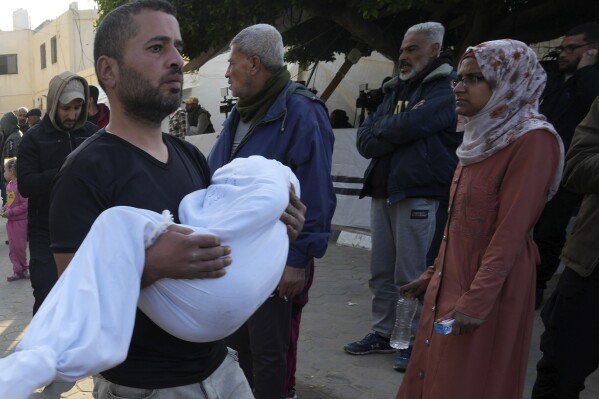 A Palestinian carries a child killed in the Israeli bombardment of the Gaza Strip at Al Aqsa Hospital in Deir al Balah on Tuesday, Feb. 20, 2024. (AP Photo/Adel Hana)