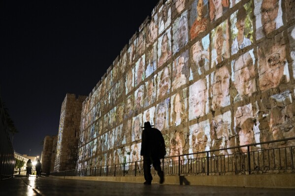 Photographs of Israeli hostages being held by Hamas militants are projected on the walls of Jerusalem's Old City, Monday, Nov. 6, 2023. (AP Photo/Leo Correa)