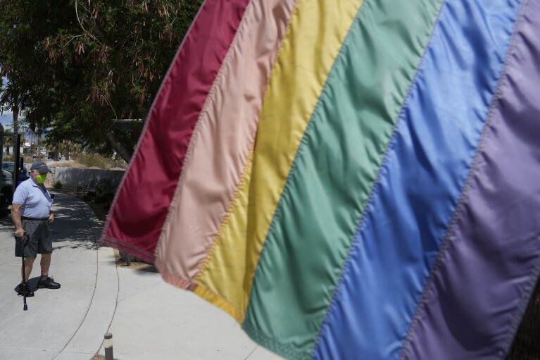 Resident Alex Smariga walks past a pride flag while returning from a physical therapy session at Stonewall Gardens, a LGBTQ+ assisted living facility, Tuesday, Aug. 15, 2023, in Palm Springs, Calif. The number of services such as nursing homes and assisted living centers that are geared toward serving the LGBTQ+ community is increasing, though such facilities remain uncommon. (AP Photo/Marcio Jose Sanchez)