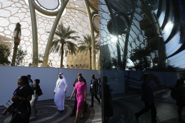 People walk through the COP28 U.N. Climate Summit near Al Wasl Dome at Expo City, Dec. 3, 2023, in Dubai, United Arab Emirates. (AP Photo/Peter Dejong)