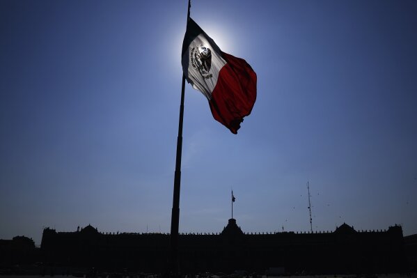 FILE - A Mexican flag waves in front of The National Palace, the office of the president, in Mexico City's main square, the Zocalo, at sunrise, April 24, 2023. Mexico's general elections, including presidential, are set for June 2, 2024. (AP Photo/Marco Ugarte, File)
