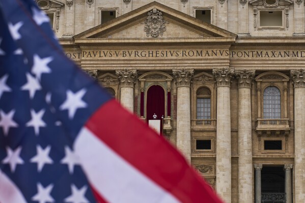 A flag from the United States waves from the crowd as Pope Leo XIV appears at the central balcony of St. Peter's Basilica for his first Sunday blessing after his election, in St. Peter's Square at the Vatican, Sunday, May 11, 2025.(AP Photo/Bernat Armangue)
