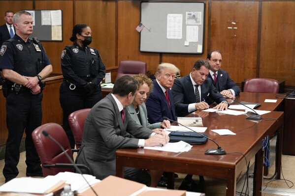 FILE - Former President Donald Trump, center, appears in court for his arraignment, Tuesday, April 4, 2023, in New York. Trump’s history-making criminal trial is set to start Monday, April 15, with a group of 12 jurors and six alternates chosen to decide whether Trump is guilty of a crime. The idea is to get people who are willing to put their personal opinions aside and make a decision based on the evidence. (AP Photo/Seth Wenig, Pool)