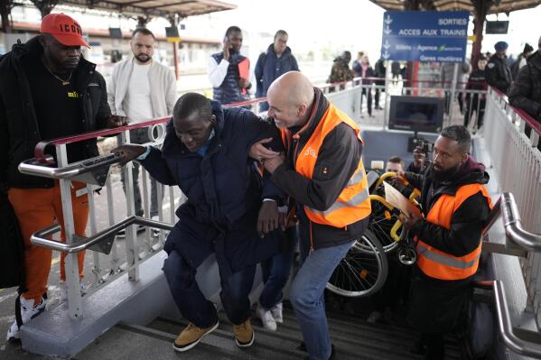 A disable man is helped climbing the stair to access the platform Wednesday, April 26, 2023 at the Melun train station, outside Paris. An influential disabled rights group in France is boycotting a conference on disability Wednesday with French President Emmanuel Macron, amid frustration at dismal accessibility for people in wheelchairs and with other mobility challenges -- and years of unmet promises to make things better ahead of the Paris 2024 Olympic and Paralympic Games. (AP Photo/Christophe Ena)