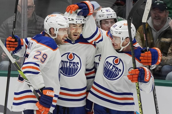 Edmonton Oilers' Evan Bouchard, second rom right, celebrates an overtime goal with teammates Leon Draisaitl (10) and Derek Ryan (11) during the third period an NHL hockey game against the Dallas Stars in Dallas, Saturday, Feb. 17, 2024. (AP Photo/LM Otero)