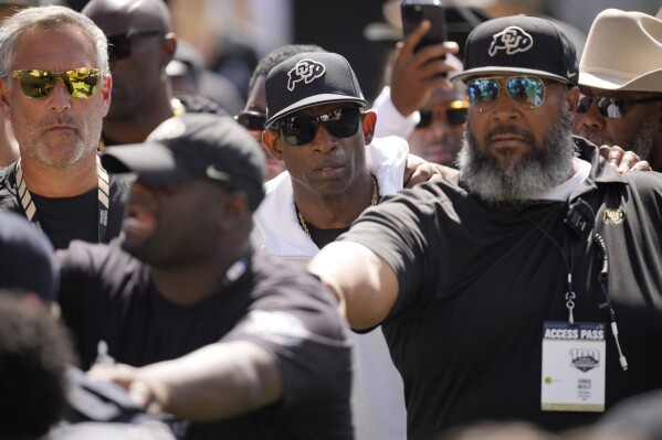 Colorado head coach Deion Sanders, center, is escorted off the field after the second half of an NCAA college football game against Nebraska Saturday, Sept. 9, 2023, in Boulder, Colo. (AP Photo/David Zalubowski)