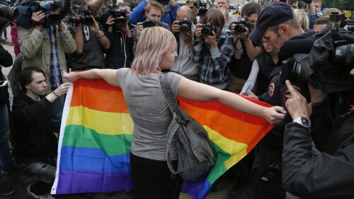 FILE - A gay rights activist stands with a rainbow flag, in front of journalists, during a protesting picket at Dvortsovaya (Palace) Square in St. Petersburg, Russia, on Aug. 2, 2015. The upper house of Russia's parliament on Wednesday July 19, 2023 unanimously approved a bill outlawing gender-affirming procedures, sending the measure to President Vladimir Putin to be signed into law. (AP Photo, File)