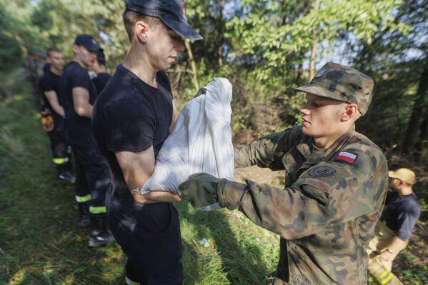 Soldiers fill and arrange sandbags to help strengthen the embankments and to prevent flooding near the city of Wroclaw, southwestern Poland, Tuesday, Sept. 17, 2024. (AP Photo/Krzysztof Zatycki)