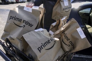 FILE - Amazon Prime Now bags are loaded for delivery outside a Whole Foods store on Feb. 8, 2018, in Cincinnati. Thousands of delivery drivers filed legal claims against Amazon on Tuesday, June 11, 2024, alleging the company's classification of them as independent contractors instead of employees has led to unpaid wages and other types of financial loss. (AP Photo/John Minchillo, File)