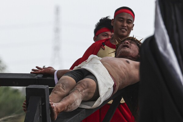Ruben Enaje se šklebí, že byl přibit na kříž během rekonstrukce utrpení Ježíše Krista v rámci rituálů Velkého pátku v San Pedro Cutud, severně od Manily na Filipínách, pátek 29. března 2024. (AP Photo/Gerard V. Carreon )