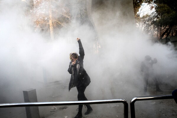 In this photo taken by a person not employed by the Associated Press and obtained by the AP outside Iran, a university student attends a protest inside Tehran University after a smoke grenade was thrown by anti-riot Iranian police, in Tehran, Iran, Dec. 30, 2017. (AP Photo, File)