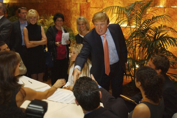 FILE - Donald Trump greets potential candidates for "The Apprentice" TV reality show during the first day of auditions for the shows next season, Friday, July 30, 2004, in New York. A producer's new account of Trump's behavior on "The Apprentice" is resurfacing allegations about whether he mistreated Black people who appeared on the show. (AP Photo/Jennifer Szymaszek, File)