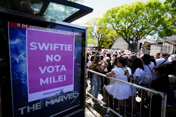 Fans of Taylor Swift wait for the doors of Monumental stadium where she will perform her Eras Tour concert, where a sign reads "Swift does not vote for Milei," referring to presidential candidate Javier Milei, in Buenos Aires, Argentina, Thursday, Nov. 9, 2023. Milei will face Economy Minister Sergio Massa in a run-off election on Nov. 19. (AP Photo/Natacha Pisarenko)