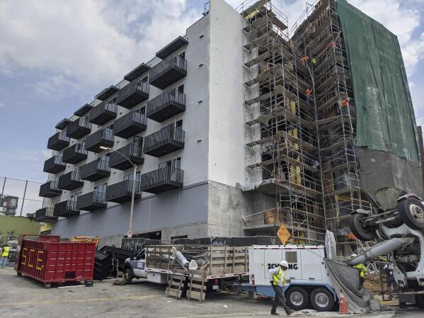 In this June 18, 2021, photo, construction workers finish the exterior of an apartment building downtown Los Angeles. California Gov. Gavin Newsom on Thursday, Sept. 16, 2021, approved two measures to slice through local zoning ordinances as the most populous state struggles with soaring home prices, an affordable housing shortage and stubborn homelessness. Newsom also signed a bill extending a 2019 law designed to make it easier to build more housing throughout the state. (AP Photo/Damian Dovarganes)