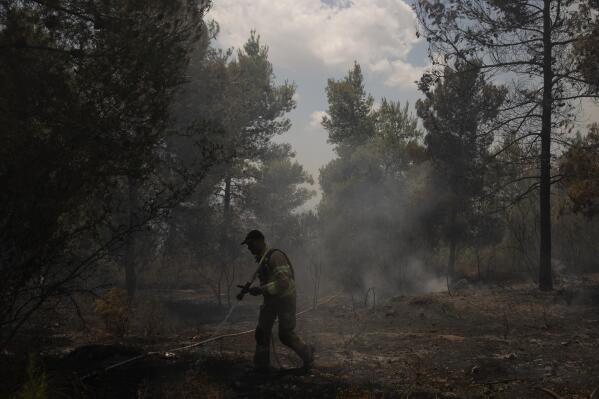An Israeli firefighter works to extinguish a fire, on the second day of wildfires near Jerusalem, Monday, Aug. 16, 2021. Israel Fire and Rescue service said in a statement on Monday, that 45 firefighting teams accompanied by eight planes were working to contain five fires in the forested hills west of the city. (AP Photo/Maya Alleruzzo)