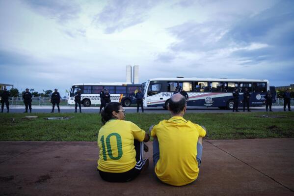 A couple of supporters of former President Jair Bolsonaro observe the movement of military police during an abortive protest organized by supporters of former President Jair Bolsonaro, in Brasilia, Brazil, Wednesday, Jan. 11, 2023. Despite being widely announced by social media, the protests did not take place and did not have supporters of the former president. (AP Photo/Gustavo Moreno)