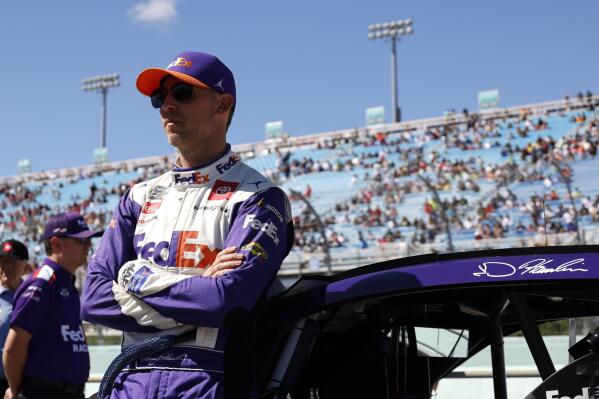 Driver Denny Hamlin leans on his car before a NASCAR Cup Series auto race at Homestead-Miami Speedway, Sunday, Oct. 23, 2022, in Homestead, Fla. (AP Photo/Terry Renna)