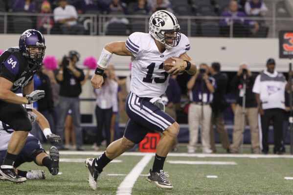 FILE - BYU quarterback Riley Nelson (13) rushes the ball past TCU defensive tackle D.J. Yendrey (94) during the first half of an NCAA college football game at Cowboys Stadium, Oct. 28, 2011, in Arlington, Texas. With BYU coming in this season, the Big 12 has three private Christian schools from different denominations that are playing major college football. After the past 12 seasons as an independent, the Cougars are now in the same league with Baylor and TCU — whose 118-game “Revivalry” dates back to a scoreless tie in 1899. (AP Photo/LM Otero, File)