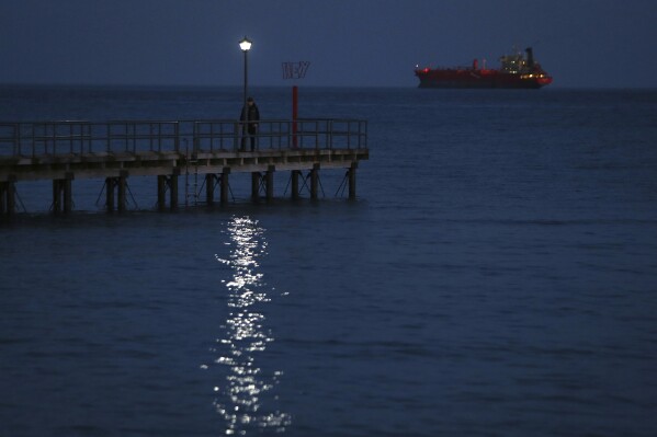 FILE - A man walks on a dock as a ship seen in the background in southern port city of Limassol, Cyprus, Friday, Feb. 23, 2018. Cyprus is working out with partners in the European Union and the Middle East the logistics to establish a sea corridor to deliver a stream of vital humanitarian aid to Gaza from the island’s main port of Limassol once the situation on the ground permits it. (AP Photo/Petros Karadjias, File)