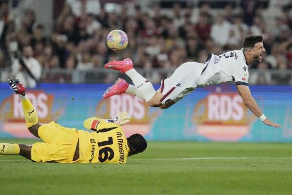 AC Milan's goalkeeper Mike Maignan, left, and Bologna's Riccardo Orsolini challenge for the ball during the Italian Cup final soccer match between AC Milan and Bologna at Rome's Olympic Stadium, Wednesday, May 14, 2025. (AP Photo/Gregorio Borgia)