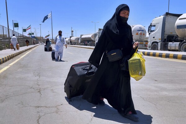 Pakistanis, who were stuck in Iran due to Israeli strikes on Iran, walk toward immigration counter after entering in homeland through Taftan, a joint border crossing point on Pakistan Iran border, Wednesday, June 18, 2025. (AP Photo/Fateh Muhammad)