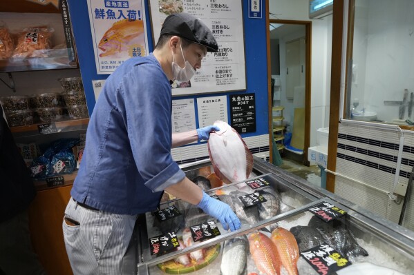 A staff member holds a flounder from Fukushima at Sakana Bacca, a seafood retailer, on Oct. 31, 2023, in Tokyo. Fishing communities in Fukushima feared devastating damage to their businesses from the tsunami-wrecked nuclear power plant’s ongoing discharge of treated radioactive wastewater into the sea. Instead, they're seeing increased consumer support as people eat more fish, a movement in part helped by China’s ban on Japanese seafood. (AP Photo/Eugene Hoshiko)