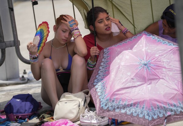 Taylor Swift fans wait for the doors of Nilton Santos Olympic stadium to open for her Eras Tour concert amid a heat wave in Rio de Janeiro, Brazil, Saturday, Nov. 18, 2023. (AP Photo/Silvia Izquierdo)