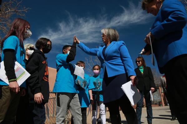 FILE - Gov. Michelle Lujan Grisham high-fives a grade school student at a bill-signing ceremony at the Francis X. Nava Elementary School on March 1, 2022, in Santa Fe, N.M. Advocates are weighing in on Democratic Gov. Michelle Lujan Grisham's plan to address an ongoing lawsuit that highlights shortcomings of the state's education system. (AP Photo/Cedar Attanasio, File)
