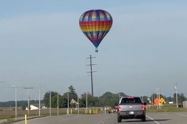 This photo provided by Debbie Wajvoda shows a hot air balloon crashing after hitting a utility pole on Sunday, June 2, 2024 east of Lowell, Ind. Federal investigators are probing the crash in northwestern Indiana that injured three people. Firefighters responded to the crash and found the balloon in a bean field. (Debbie Wajvoda via AP)