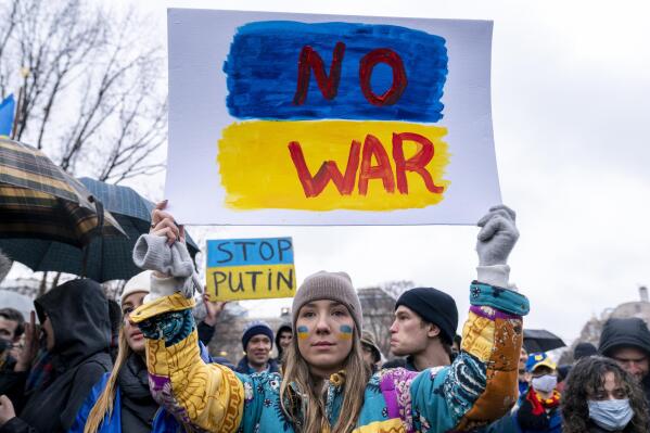 A tear rolls down through the colors of the Ukrainian flag on the cheek of Ukranian Oleksandra Yashan of Arlington, Va., as she becomes emotional while holding a sign that reads "No War" during a vigil to protest the Russian invasion of Ukraine in Lafayette Park in front of the White House in Washington, Thursday, Feb. 24, 2022. (AP Photo/Andrew Harnik)