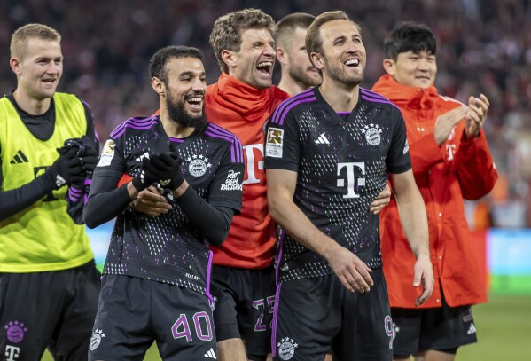 Noussair Mazraoui, from left, Thomas Müller and Harry Kane of Bayern Munich celebrate in front of the crowd after the German Bundesliga soccer match between FC Union Berlin and Bayern Munich at the An der Alten Forsterei stadium in Berlin, Germany, Saturday, April 20, 2024. (Andreas Gora/dpa via AP)