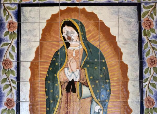 A Virgin of Guadalupe mural painted on tiles is seen with a destroyed face on the side of St. Elisabeth Catholic Church in the Van Nuys section of Los Angeles on Wednesday, April 28, 2021. A man used a sledgehammer to smash the face of a Virgin of Guadalupe mural and was recorded on security camera video during the attack that happened around 1:40 a.m. on April 21. (AP Photo/Richard Vogel)