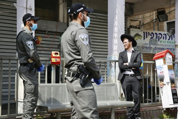 FILE - In this Thursday, April 2, 2020 file photo, Israeli border police officers question an Ultra orthodox man as part of the government's measures to help stop the spread of the coronavirus in the orthodox city of Bnei Brak, a Tel Aviv suburb, Israel. ‏On Wednesday, Netanyahu ordered a police cordon around the largely ultra-Orthodox city of Bnei Brak, east of Tel Aviv, to limit movement to and from the city. Bnei Brak has the second highest number of coronavirus cases in Israel. (AP Photo/Ariel Schalit, File)